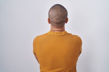 Beyaz arka planda duran sakallı İspanyol adam çapraz kollarla başka tarafa bakıyor. 