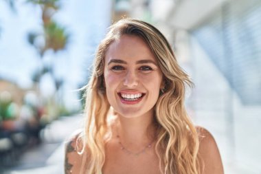 Sokakta kendine güvenen genç sarışın kadın gülümsüyor