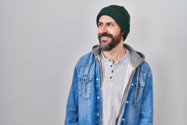 Dövmeli, yün şapkalı, yüzünde gülümseme, yüzünde doğal bir ifade olan İspanyol bir adam. Kendinden emin gülen. 