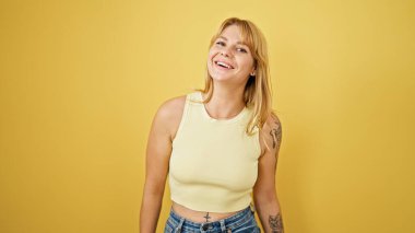 Young blonde woman smiling confident standing over isolated yellow background
