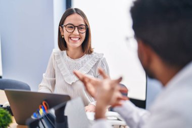 Man and woman business workers using laptop speaking at office