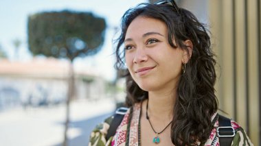 Young beautiful hispanic woman smiling confident looking to the side at street