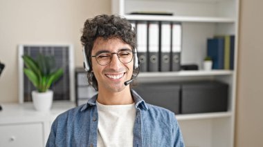 Ofiste gülümseyen kulaklık kullanan İspanyol bir iş adamı.