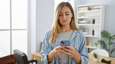 Güzel sarışın patron, ofisteki akıllı telefondan başarı mesajı atan genç bir iş kadınının cesaretini yakalıyor.