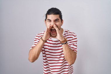 Uzun saçlı İspanyol bir adam izole edilmiş arka planda duruyor ve elleri ağzında kızgın bir şekilde bağırıyor. 