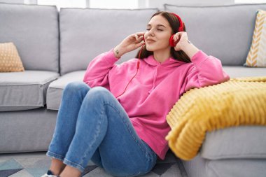 Evde oturmuş müzik dinleyen genç bir kadın.