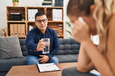 Genç Latin Psikolog Psikoloji kliniğindeki hastaya bir bardak su veriyor.