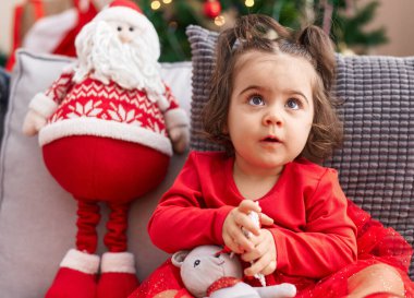 Evdeki Noel ağacının yanında oturan sevimli İspanyol kız.