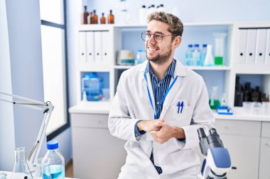 Young man scientist smiling confident speaking at laboratory
