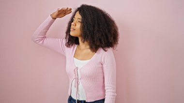 İzole edilmiş pembe arka plan arayan Afrikalı Amerikalı bir kadın.
