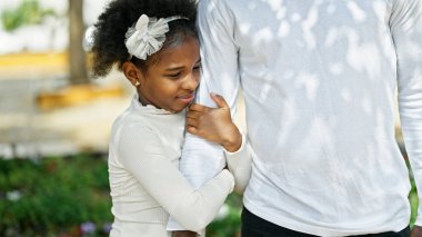 Afro-Amerikan baba ve kızı gülümsüyor. Parkta el ele tutuşuyorlar.