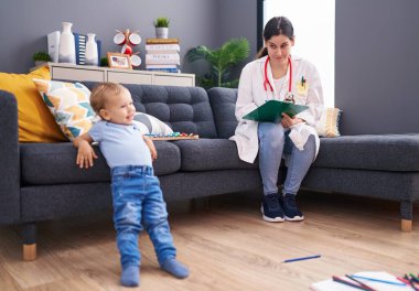 Anne ve oğul doktor evdeki çocuğu muayene eden belgeye yazıyor.