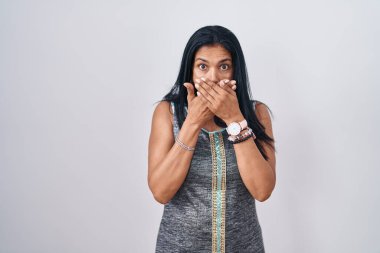 Beyaz arka planda duran olgun İspanyol kadın yanlışlıkla elleriyle ağzını kapatırken şok oldu. gizli kavram. 