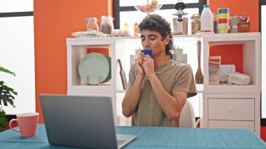 Yemek odasındaki masada oturan ve kredi kartını öpen İspanyol genç adam.