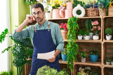 Çiçekçide akıllı telefondan konuşan İspanyol bir çiçekçi.