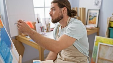 Sanat stüdyosunda resim çizen genç bir İspanyol.