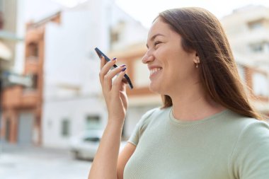 Genç, güzel bir kadın, gülümsüyor. Kendine güveniyor. Akıllı telefondan konuşuyor.