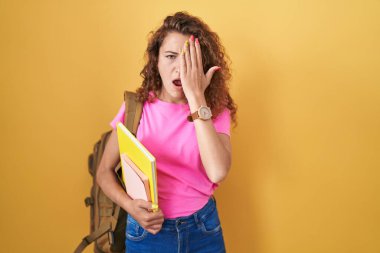 Öğrenci çantası takan, elinde kitap tutan, esnemekten yorgun, yarı yüz, göz ve ağız kaplayan beyaz bir kadın. Yüzüm acıyor.. 