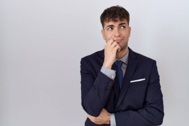 Takım elbiseli ve eli çenesinde kravatlı İspanyol bir iş adamı soru sormayı düşünüyor, düşünceli bir ifade. Düşünceli bir yüzle gülümsüyor. şüphe kavramı. 