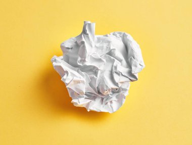 One white crumpled paper ball over isolated yellow background