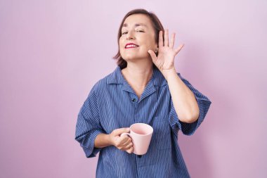 Orta yaşlı İspanyol bir kadın kahve içerken kulağından kulaklarına gülümseyerek dedikoduları ve dedikoduları dinliyor. Sağırlık kavramı. 