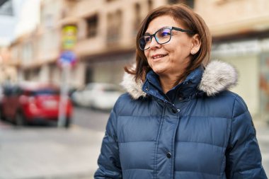 Orta yaşlı bir kadın sokakta gözlük takıyor.