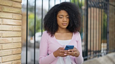 Sokakta akıllı telefon kullanan Afro-Amerikalı kadın.