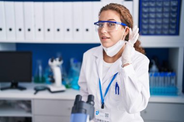 Bilim adamlarının laboratuvarında çalışan genç, beyaz bir kadın kulağından girip kulağına fısıldayarak dedikoduları ve dedikoduları dinliyor. Sağırlık kavramı. 