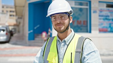 Kafkasyalı genç mimar inşaat alanında kendine güvenerek gülümsüyor.