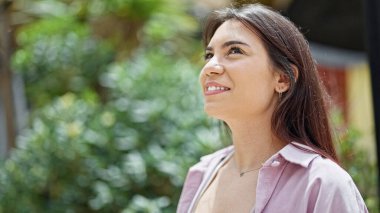 Young beautiful hispanic woman smiling confident looking to the sky at park