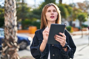 Parkta yüzü ciddi bir şekilde dokunmatik kağıda yazan genç sarışın kadın.