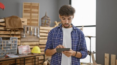 Stoik yüzlü genç Arap marangoz marangozluk atölyesindeki talaş ve kerestelerin arasında ustalıkla geziyor.