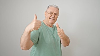İzole edilmiş beyaz arka plan üzerinde baş parmağıyla gülümseyen orta yaşlı gri saçlı bir adam.