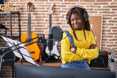 Afrikalı Amerikalı kadın müzisyen gülümsüyor. Kollarını kavuşturup müzik stüdyosunda el kol hareketi yapıyor.