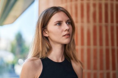 Sokakta ciddi bir ifadeyle yan tarafa bakan genç sarışın kadın.