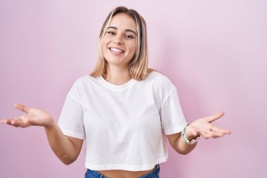 Pembe arka planda duran genç sarışın kadın gülümseyen, yardım eli uzatan ve kabullenen biri.. 