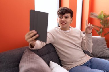 Kanepede oturan dokunmatik dokunmatik olmayan genç bir adam bir fikir ya da soru işareti ile gülümsüyor. 