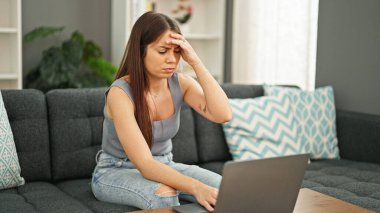 Evdeki kanepede dizüstü bilgisayar kullanan güzel İspanyol kadın.