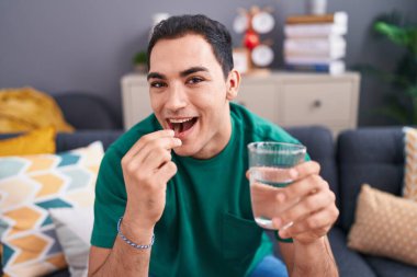 Evdeki kanepede oturup hap alan genç bir İspanyol.