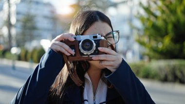 Sırt çantalı genç İspanyol kadın turist sokakta kamerayla fotoğraf çekiyor.