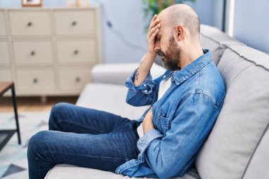 Young bald man suffering for head and stomach ache at home