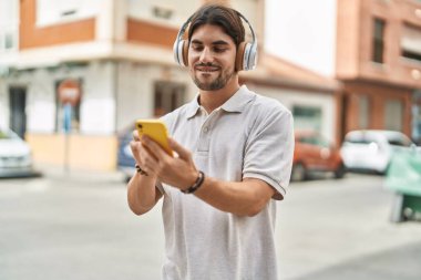 Sokakta müzik dinlerken kendinden emin gülümseyen İspanyol genç adam.