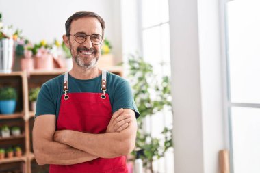 Middle age man florist smiling confident standing with arms crossed gesture at florist