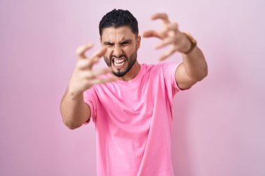 Pembe arka planda duran İspanyol genç adam öfkeyle bağırıyor, elleri boğazlamaya çalışıyor, deli gibi bağırıyor. 