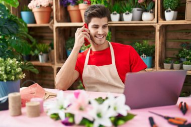 Çiçekçide dizüstü bilgisayar kullanarak konuşan İspanyol çiçekçi.