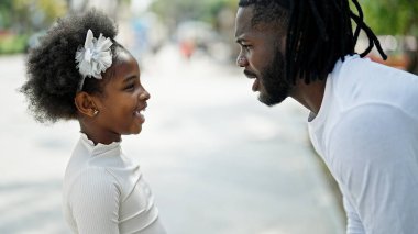 Afro-Amerikan baba ve kızı gülerek sokakta bir arada duruyorlar.