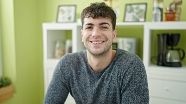 Yemek odasındaki masada kendinden emin gülümseyen İspanyol genç adam.