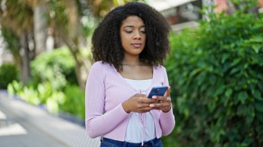 Parkta akıllı telefon kullanan Afro-Amerikalı kadın.