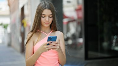 Sokakta ciddi yüzlü akıllı telefon kullanan güzel bir kız.