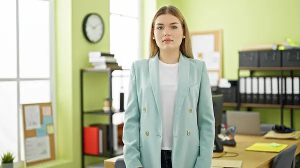 Young blonde woman business worker standing with serious face at office